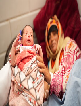 A midwife hands over a newborn baby to her mother at the newly rehabilitated maternity wing of Al Mokha Hospital in Taizz, Yemen