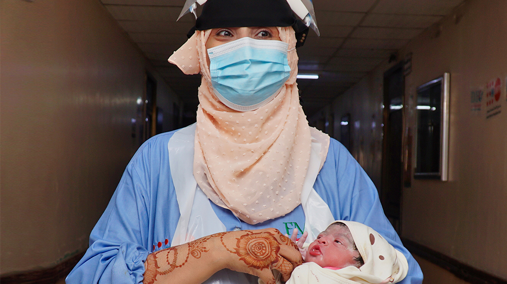 Midwife carries a newborn baby at a UNFPA-supported health facility in Aden, Yemen  ©UNFPA Yemen