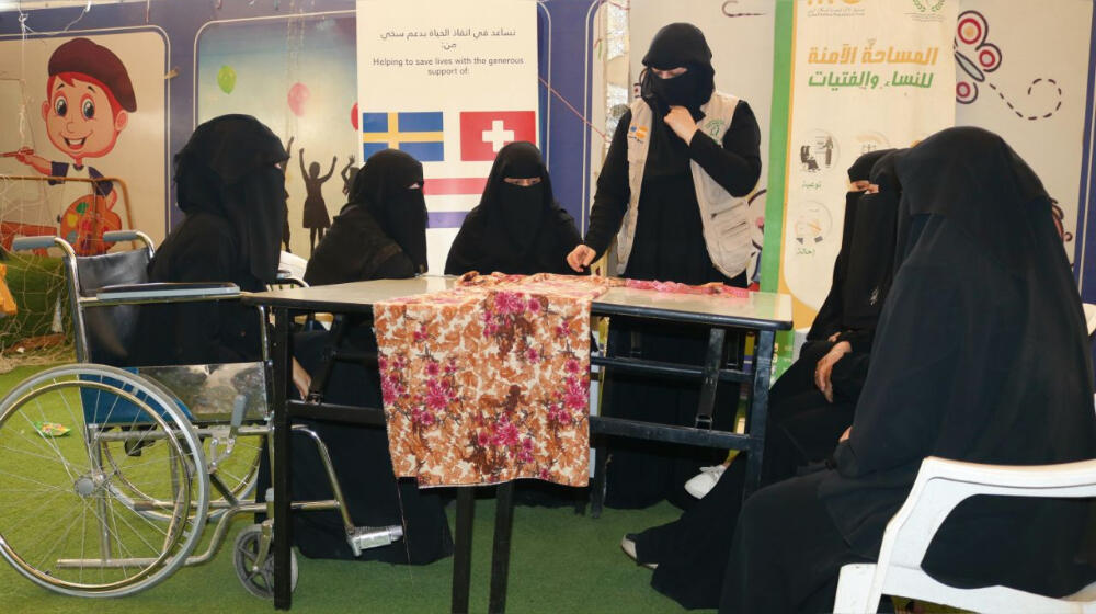 Nabila sits with a group of women as they learn how to sew and tailor clothes in a livelihood skills training course, held at a 