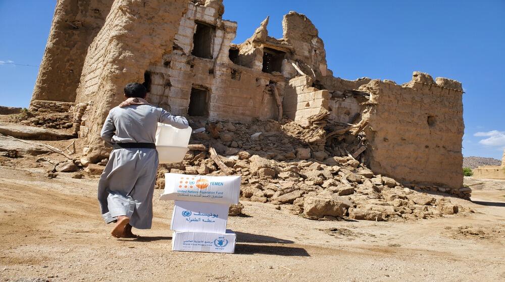 A displaced man carries an RRM kit after heavy flooding wreck their homes ©UNFPA/ YARD